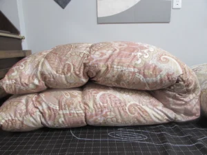 二つに折りたたまれたピンク系羽毛布団