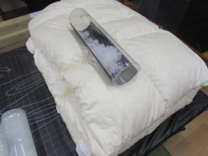 白い羽毛布団と透明な筒に入った羽毛