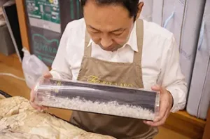 透明な筒に入った羽毛を見つめる店主